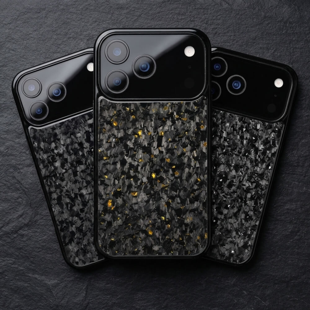 Product photograph of three black iPhone cases featuring shattered forged carbon fiber texture with golden metallic flecks on the central case laid on a dark slate surface displaying prominent triple camera lenses